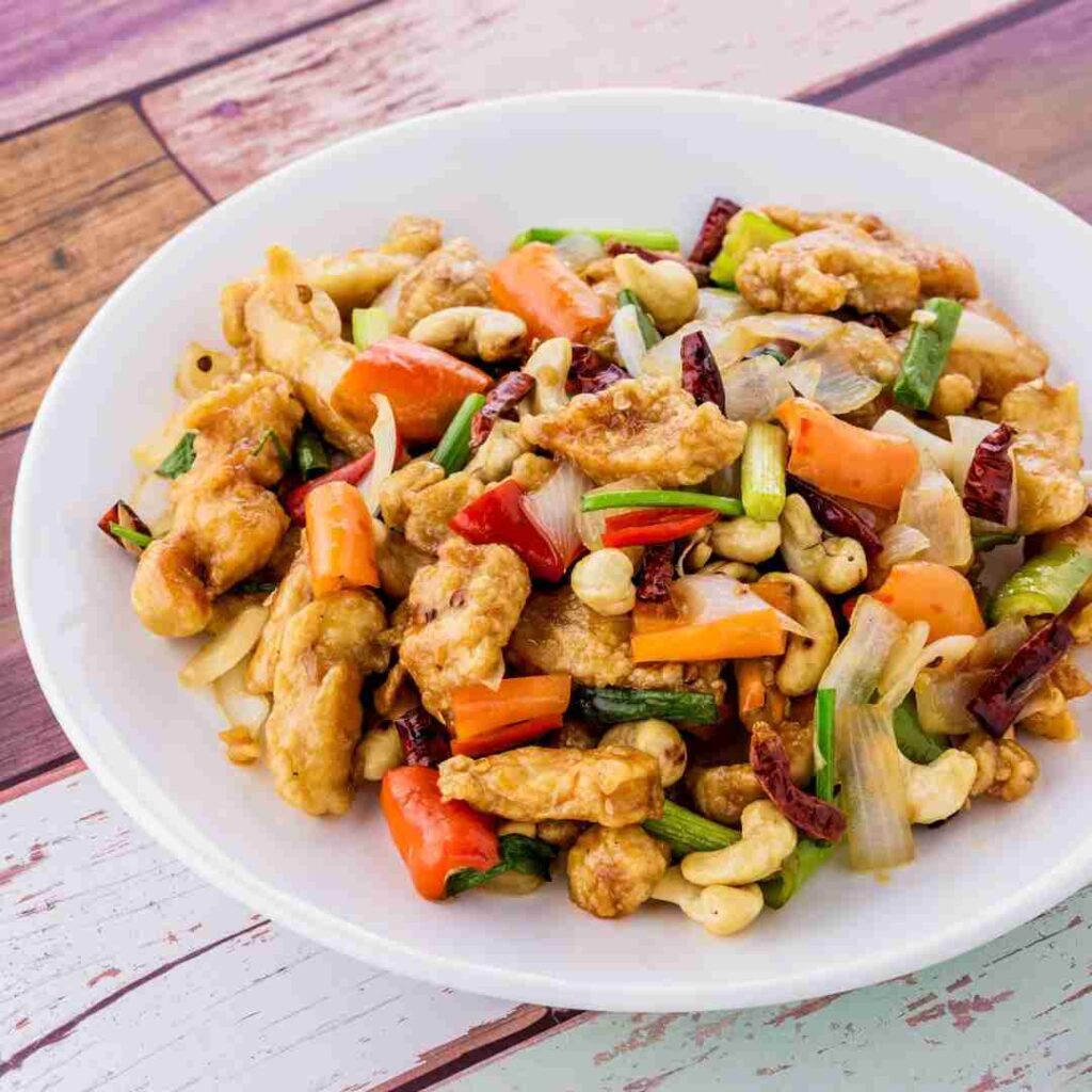 A colorful plate of Gai Pad Med Mamuang, a popular Halal Thai stir-fry dish featuring tender chicken and crunchy cashew nuts.