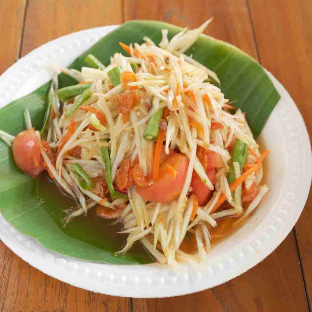 A fresh and spicy bowl of Som Tum, an authentic Halal Thai green papaya salad, a refreshing dish to try alongside grilled chicken in Bangkok.